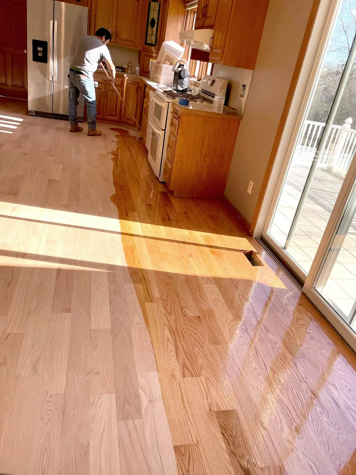 MJP Flooring team applying polyurethane finish to hardwood floors